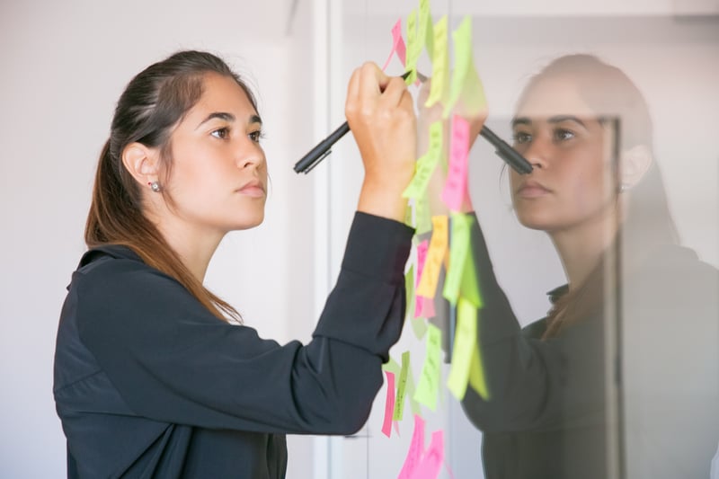 young-latin-businesswoman-writing-sticker-with-marker-focused-confident-beautiful-brunette-female-manager-sharing-idea-project-making-note-brainstorming-business-training-concept
